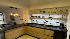 A modern kitchen with a central island, wooden cabinets, and a backsplash with a mosaic pattern.