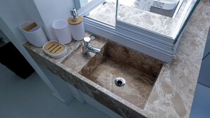 A bathroom with a marble sink, a window, and a towel rack. - KITNET in the heart of Salvador/BA: Barra (Barra Salvador)