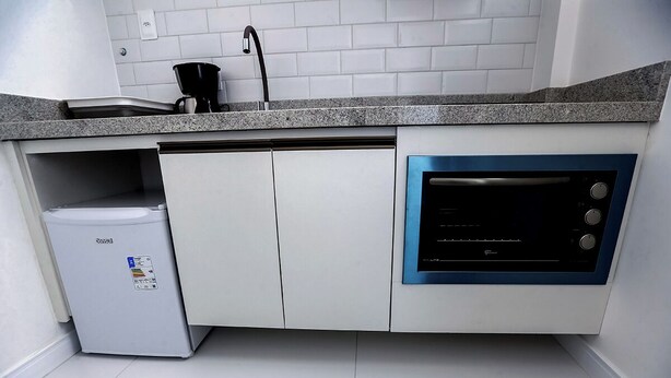 A compact kitchen with a built-in oven, a coffee maker, and a mini fridge. - KITNET in the heart of Salvador/BA: Barra (Barra Salvador)