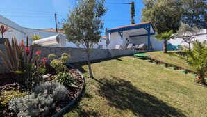 A well-maintained garden with various plants and a patio area with outdoor furniture.