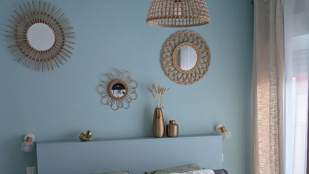 A bedroom with a bed, a hanging light fixture, and wall decor.
