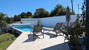 A poolside area with two lounge chairs, a small table, and a potted plant.