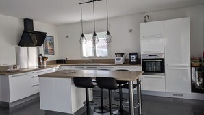 A modern kitchen with a central island, stainless steel appliances, and pendant lighting.