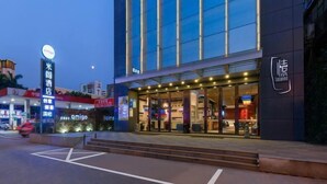 Un hotel moderno con fachada de vidrio, entrada visible e iluminación exterior destacada.