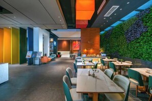 A modern restaurant with a green wall, multiple tables, and chairs. - Amigo Hotel (Guangzhou Zengcheng Xintang South High Speed Railway Station) (Guangzhou)