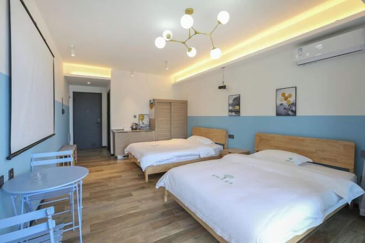 A hotel room with two beds, a small table, and a desk.