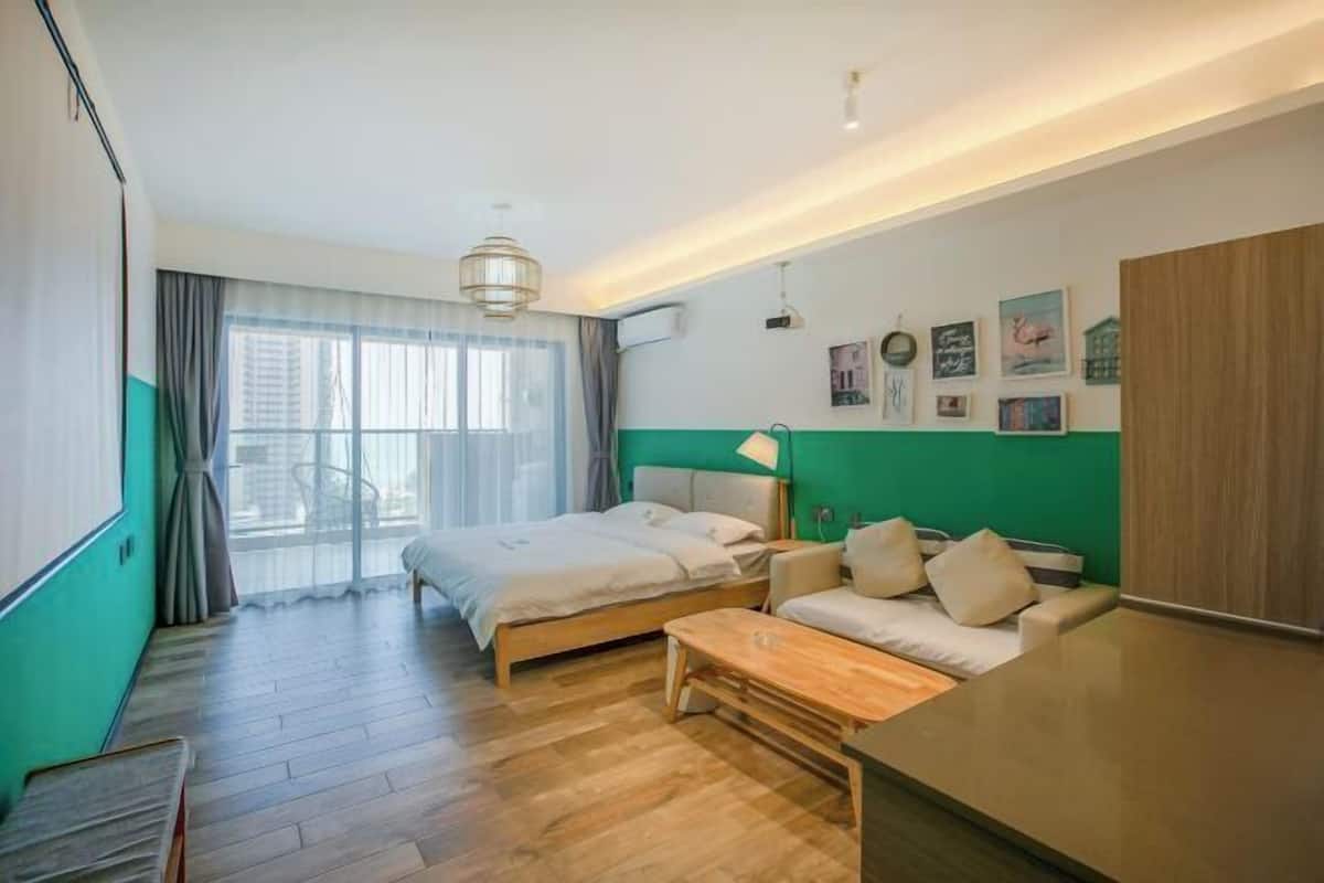 A hotel room with a bed, a sofa, a desk, and a large window.