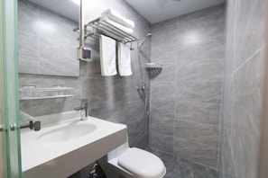 A modern bathroom with a white sink, a toilet, and a shower.
