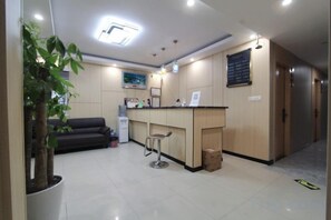 A hotel lobby with a reception desk, a bar area, a sofa, and a potted plant. - Haoshang Business Hotel (Shanghai)