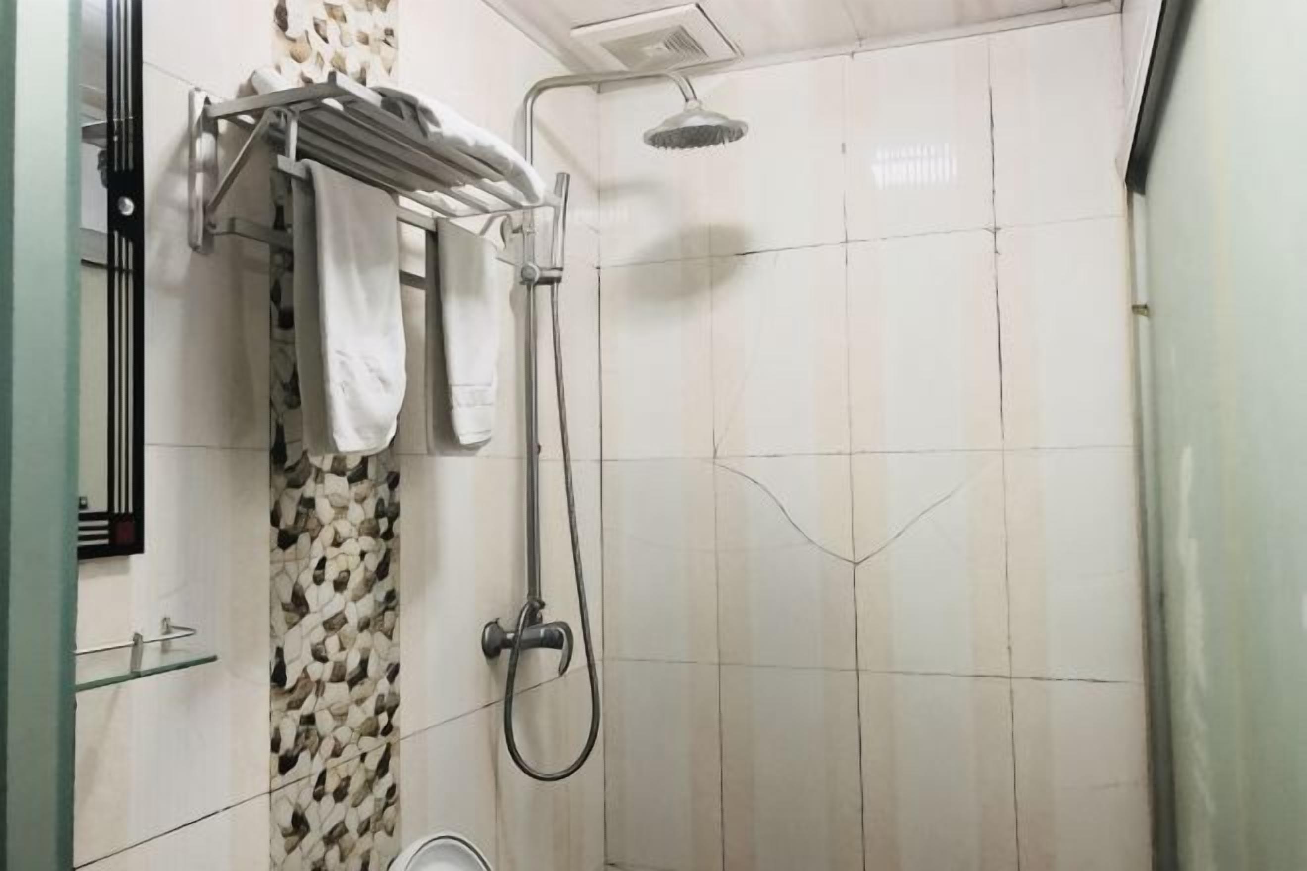 Ducha con cabezal de ducha de mano, barra para toallas con toallas y pared con diseño.