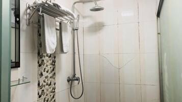Ducha con cabezal de ducha de mano, barra para toallas con toallas y pared con diseño.