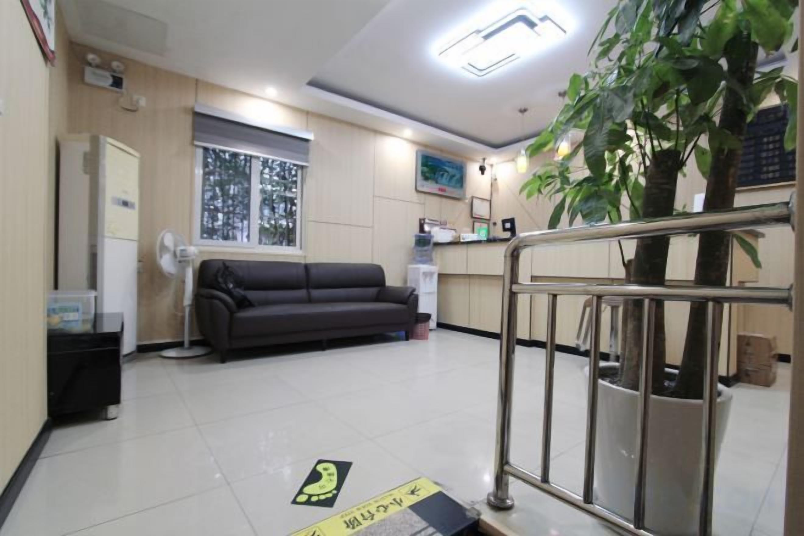 A reception area with a sofa, a desk, a plant, and a sign on the floor.