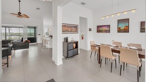 A spacious living area with a modern kitchen, dining area, and a large window offering a view of the outdoors. - EV_149 - 5 Bed 3 Bath Home with Private Screened-In Pool, Games Room (Davenport)