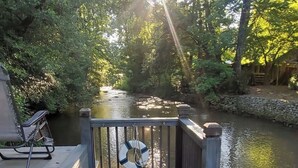 Un molo di legno con un salvagente appeso alla ringhiera, che si protende su un fiume tranquillo, circondato da alberi.
