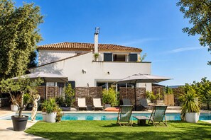 Uma casa moderna de dois andares com piscina, área de estar ao ar livre e um jardim bem cuidado.
