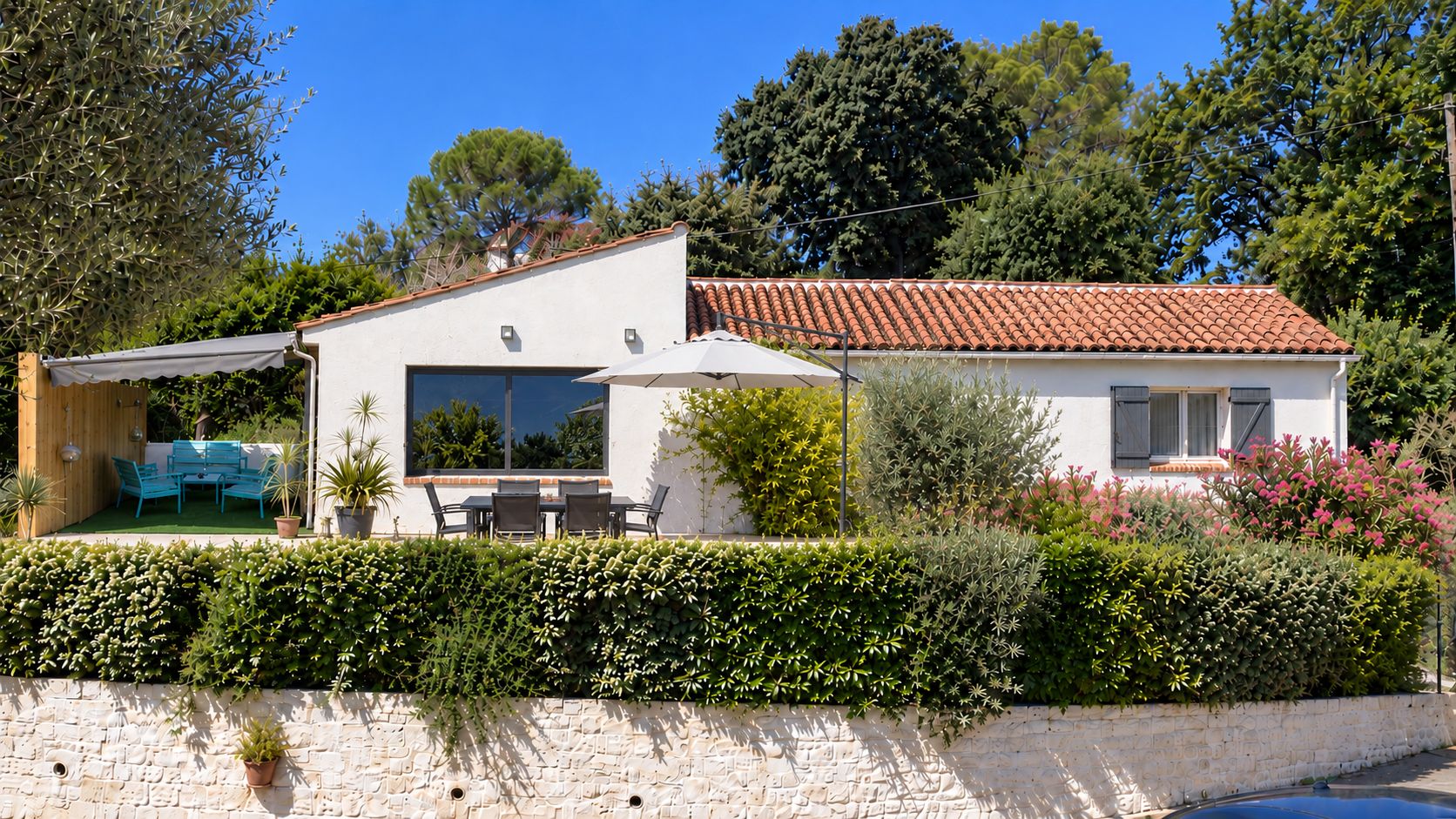 Une maison à deux étages avec un patio, un espace salon extérieur et un mur en pierre.