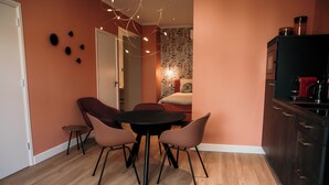 A compact living space with a dining area, kitchenette, and a cozy bedroom visible through an open door.