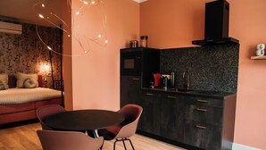 A modern kitchen with a black microwave, a coffee maker, and a toaster. There is a dining table with two chairs.