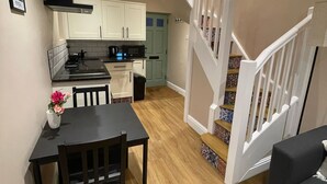 Un espace de vie compact comprenant un coin repas, une cuisine et un escalier.