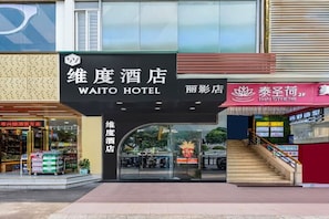 The exterior of the Waito Hotel with a clear entrance, a visible staircase, and a Thai Herb shop adjacent to it. - Waito Hotel (Guangzhou Kecun Metro Station Liying Plaza) (Guangzhou)