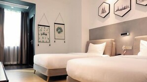 Une chambre d’hôtel avec deux lits, un bureau et des tableaux encadrés au mur.