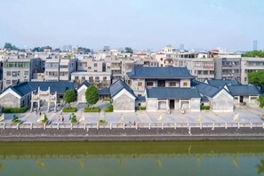 Una hilera de edificios modernos con techos planos, un sendero pavimentado y una masa de agua al frente.