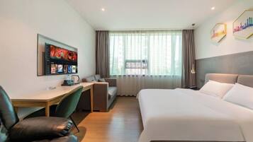 Una habitación de hotel con cama, escritorio y zona de estar.