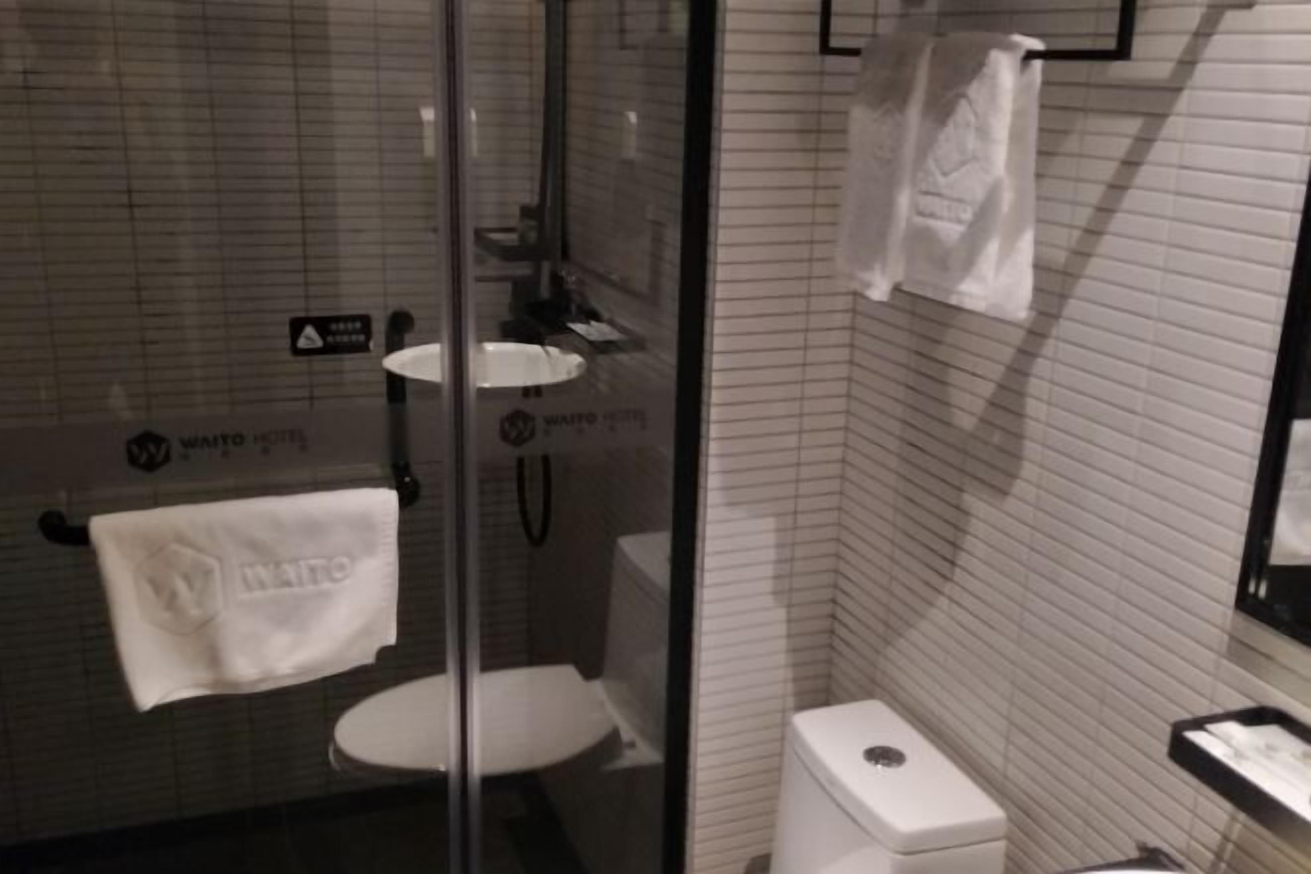 A bathroom with a glass shower enclosure, a white toilet, and a sink.