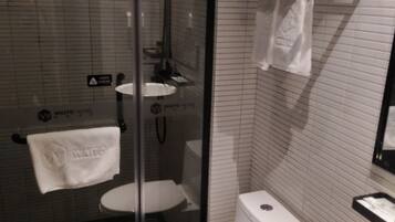 A bathroom with a glass shower enclosure, a white toilet, and a sink.