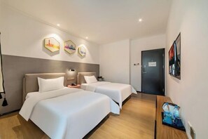 Ett hotellrum med två sängar, ett skrivbord, en kaffemaskin och sexkantig väggdekoration.