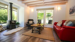Ein gemütlicher Wohnraum mit einem roten Sofa, einem schwarzen Ledersessel, einem Holztisch und einem Kamin.