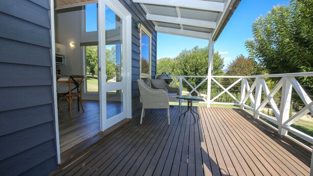 Eine Holzterrasse mit überdachtem Bereich, Korbstühlen und einem Tisch.