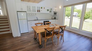 A modern kitchen with white cabinets, a wooden dining table, and chairs.
