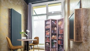 Un rincón acogedor para leer con una estantería de madera, dos sillones, una mesita y un radiador.