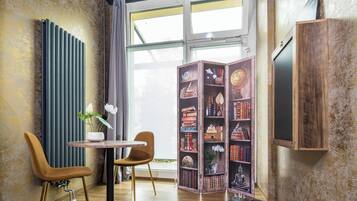 Eine gemütliche Leseecke mit einer Holzbibliothek, zwei Sesseln, einem kleinen Tisch und einer Heizung.