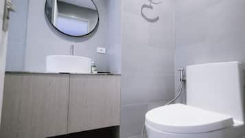 A modern bathroom with a white sink, a round mirror, and a toilet.