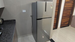 Une cuisine équipée d’un réfrigérateur en acier inoxydable, d’un plan de travail en granit et d’une porte en bois.