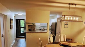 A dining area with a round table, chairs, and a hanging light fixture.
