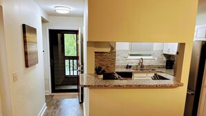 A modern kitchen with granite countertops, a built-in oven, and a stainless steel refrigerator.