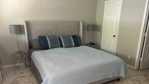 A bedroom with a large bed, two bedside lamps, a nightstand, and a door. - Serenity :3-bedroom bungalow in phenomenal Flower Mound with Wi Fi, AC, Parking (Flower Mound)