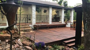 A patio with a wooden deck, stone pillars, and hanging planters. - Serenity :3-bedroom bungalow in phenomenal Flower Mound with Wi Fi, AC, Parking (Flower Mound)