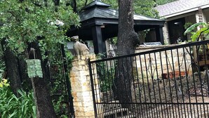 A gated area with a stone pillar, a metal gate, and a building with a dark roof. - Serenity :3-bedroom bungalow in phenomenal Flower Mound with Wi Fi, AC, Parking (Flower Mound)