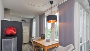 Eine moderne Küche mit einem Holztisch, einem roten Dekoelement und einer schwarzen Pendelleuchte.