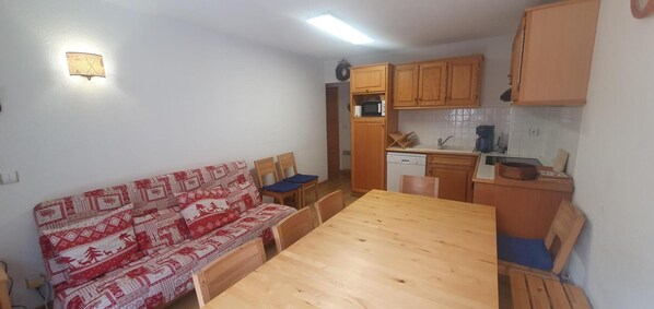 Ett kompakt bostadsutrymme med en soffa, ett matbord och ett köksområde.