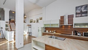 Une cuisine moderne dotée d’un plan de travail en marbre, de meubles en bois et d’un évier en acier inoxydable.