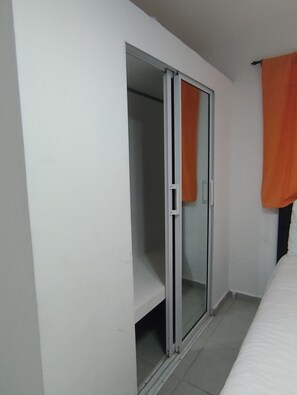 Ein Zimmer mit Schiebeglasfenster, einem Bett und einem orangenen Vorhang.