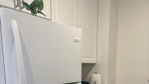 A kitchen with a white refrigerator, a trash bin, and a countertop with a paper towel holder. - Trendy apartment in Gadsden, AL (Gadsden)