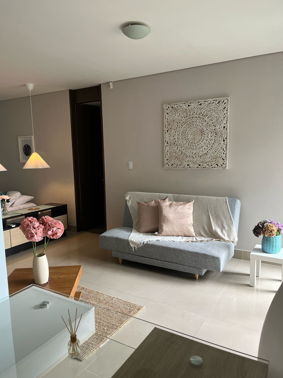 A modern living room with a grey sofa, decorative wall art, and a glass coffee table.