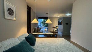 A modern hotel room with a large bed, a desk, and a view of the city.