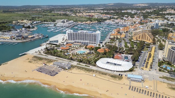 An aerial view of a coastal city with a marina, hotels, and a beach.